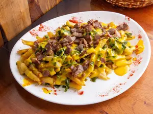 Papas fritas con cheddar, panceta y verdeo