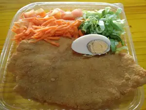 Milanesa al plato de pollo con guarnición.